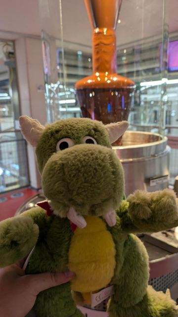 KDE mascot Konqi with chocolate manufacturing equiopment in the background