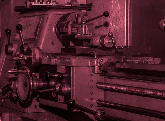 Close up of an industrial lathe with a red monochrome filter applied.