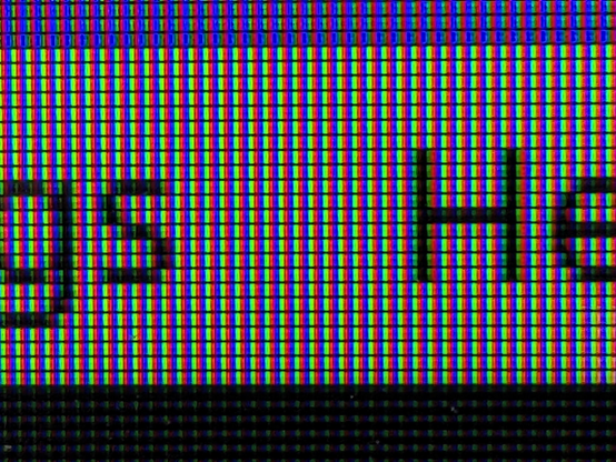 Close shot of an LCD monitor, zoomed in so that the individual sub-pixels are visible. They are arranged in a blue-green-red pattern.